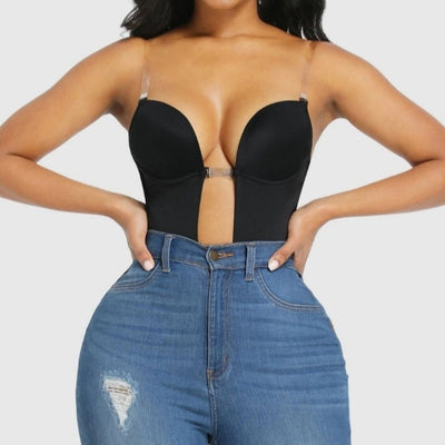 Woman wearing a black strapless top and blue jeans on a plain background shapewear
