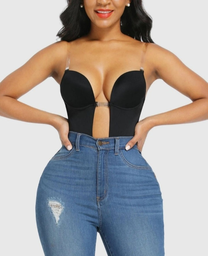 Woman wearing a black strapless top and blue jeans on a plain background shapewear